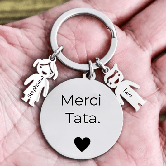 Porte-clé Merci Tata tenu dans une main, breloques enfant gravées visibles à l'échelle