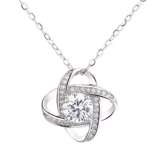 Collier trèfle porte-bonheur argenté orné de zircons sur fond blanc